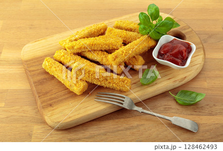 Fish fingers with basil and ketchup on a wooden table. 128462493