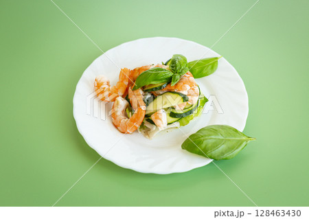 Fresh vegetable salad with shrimps and cucumbers on a green background Fresh vegetable salad with shrimps and cucumbers on a green background 128463430
