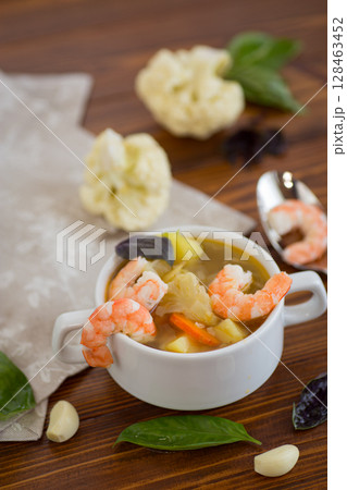 A White Cup of Warm Broth with Large Juicy Shrimp 128463452