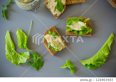 Slice of rye bread with cheese spread and greens on the table Slice of rye bread with cheese spread and greens on the table 128463483
