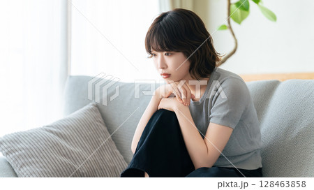 リビングのソファに座って考える女性 リビングのソファに座って考える女性 128463858