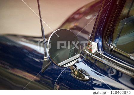 Close-Up of a Vintage Car's Side Mirror with Shiny Blue Paint 128463876