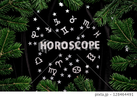 Abstract background with the inscription Horoscope on a black velvet background with fir branches. Abstract background with the inscription Horoscope on a black velvet background with fir branches. 128464491