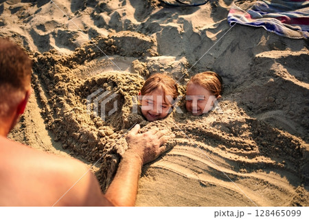 Family fun at the beach with kids playing in the sand Family fun at the beach with kids playing in the sand 128465099