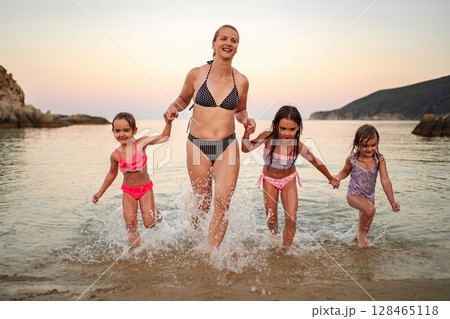 Family enjoys playful moments at the shoreline during sunset Family enjoys playful moments at the shoreline during sunset 128465118