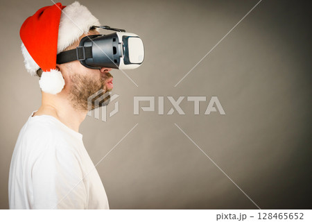 Man in virtual reality goggles and santa hat 128465652