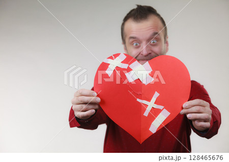Funny man holds broken heart 128465676