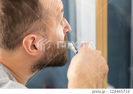 Man brushing his teeth in bathroom 128465718