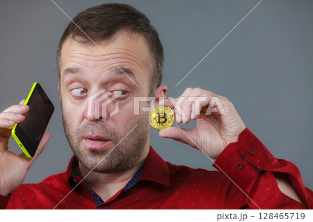 Man talking on phone holding bitcoin 128465719
