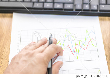 Businessman analyzes market printed on paper to improve business, business concept and strategy, blurry photo 128465954