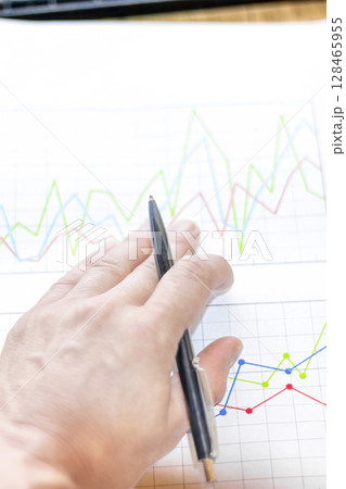 Businessman analyzes market printed on paper to improve business, business concept and strategy, blurry photo 128465955
