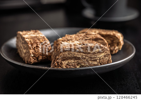 Halva with cocoa. Sweet oriental dessert on black table. 128466245