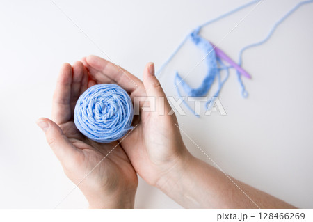 Woman holding blue yarn ball with crochet hooks on white background Woman holding blue yarn ball with crochet hooks on white background 128466269