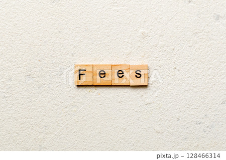 Fees word written on wood block. Fees text on cement table for your desing, Top view concept 128466314