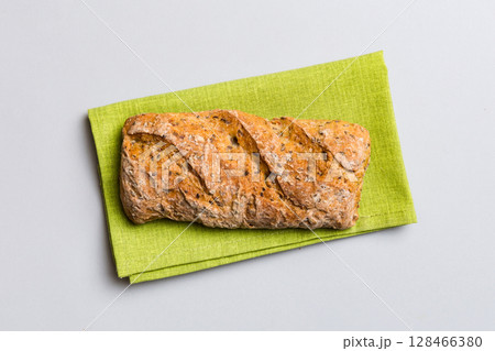 Fresh loaves of bread with wheat and gluten on a colored table. bread on napkin on rustic background, fresh bread top view 128466380