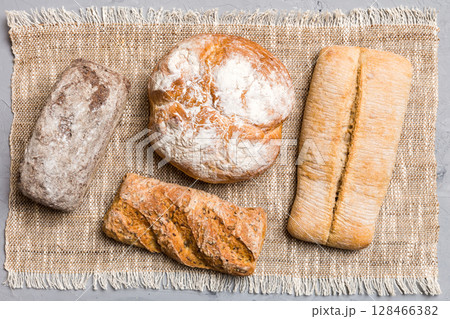 Assortment of freshly baked bread with napkin on rustic table top view. Healthy unleavened bread. French bread 128466382