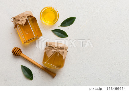 Honey jar with wooden honey dipper on white background top view with copy space. Delicious honey bottle 128466454