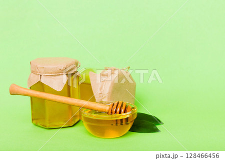 Honey in jar with leaves and honey dipper on colored background top view with copy text Honey in jar with leaves and honey dipper on colored background top view with copy text 128466456