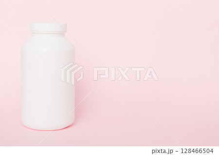 supplement pills with medicine bottle health care and medical top view. Vitamin tablets. Top view mockup bottle for pills and vitamins with green leaves, natural organic bio supplement, copy space 128466504