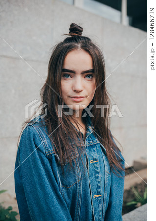 Woman with long hair is wearing a blue denim jacket 128466719