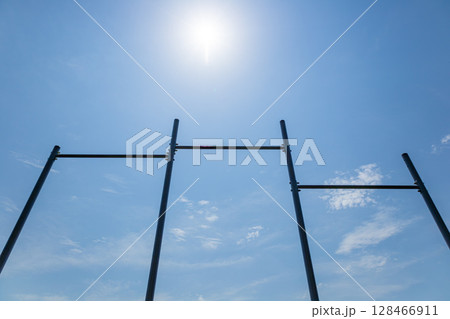 Parallel horizontal bars stand tall against a blue sky, perfect for various workout routines and promoting an active lifestyle outdoors 128466911