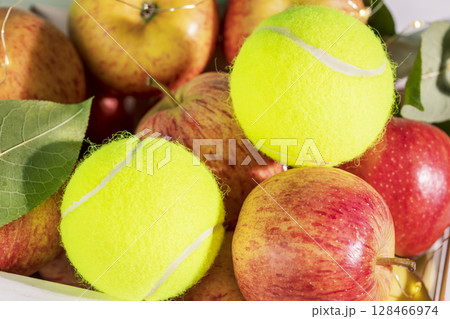 Tennis composition with close up yellow tennis balls with natural red apples. Tennis competition. Concept of Healthy sport. Selective focus 128466974