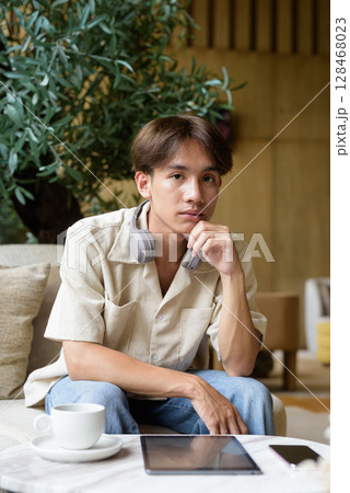 Handsome person looking at camera in coffee shop 128468023