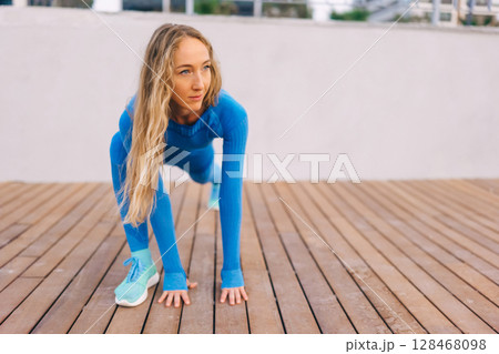 Young fitness woman in sports clothing making exercises in the street at sunny day. 128468098