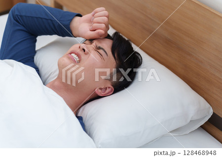 発熱してベッドで寝る男性 128468948