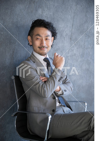 椅子に座って考えるスーツを着たビジネスマン 成功や目標、戦術や戦略を練るイメージの縦 椅子に座って考えるスーツを着たビジネスマン 成功や目標、戦術や戦略を練るイメージの縦 128469305