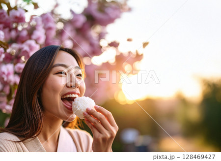 花見でおにぎりを食べる若い女性 128469427