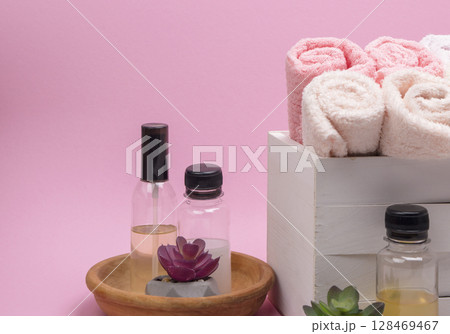 A towel, shampoo, conditioner, and soap placed on a pink surface, offering a clear side view and room for text. A towel, shampoo, conditioner, and soap placed on a pink surface, offering a clear side view and room for text. 128469467