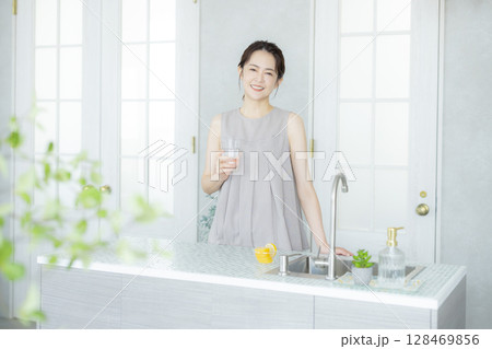 キッチンで水を飲むミドルの女性 128469856