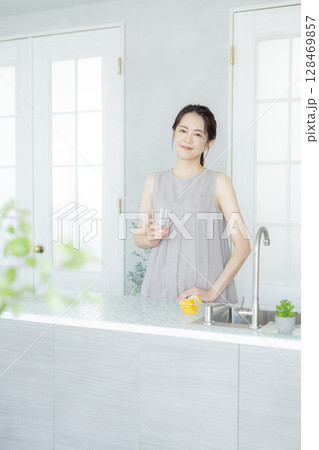 キッチンで水を飲むミドルの女性 キッチンで水を飲むミドルの女性 128469857