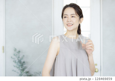 キッチンで水を飲むミドルの女性 128469859