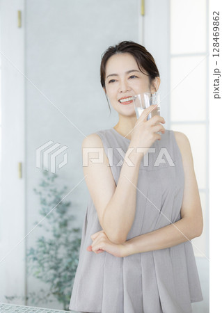 キッチンで水を飲むミドルの女性 キッチンで水を飲むミドルの女性 128469862