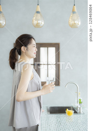 キッチンで水を飲むミドルの女性 128469864