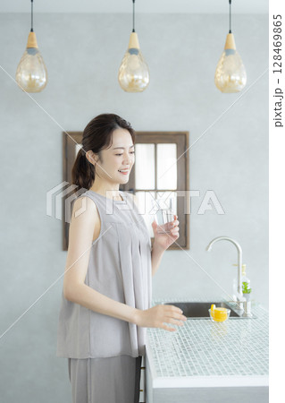 キッチンで水を飲むミドルの女性 キッチンで水を飲むミドルの女性 128469865