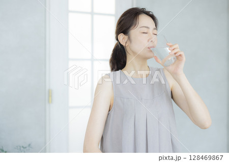 キッチンで水を飲むミドルの女性 128469867