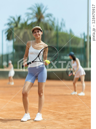Portrait of sporty woman tennis player with racket and ball in hands Portrait of sporty woman tennis player with racket and ball in hands 128470917
