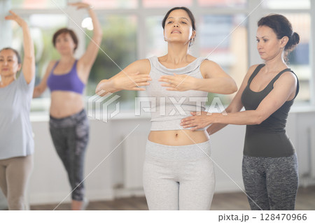 Adult woman teacher correcting beginning dancers 128470966