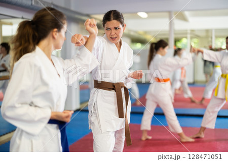 Women in self-defense training in white kimono with belts 128471051