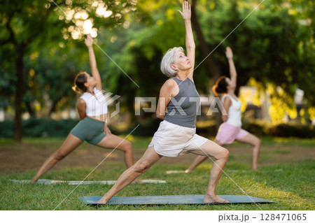 Elderly woman doing yoga in warrior pose Elderly woman doing yoga in warrior pose 128471065
