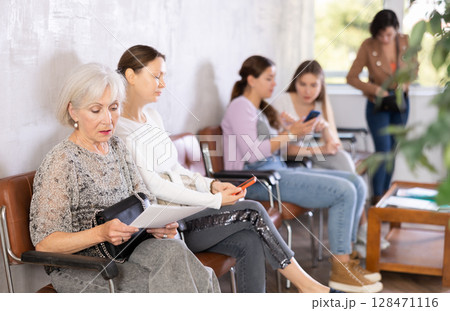 Elderly woman with documents waiting for her turn on chair 128471116