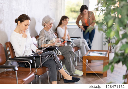 Adult woman with documents waiting for her turn on chair 128471182
