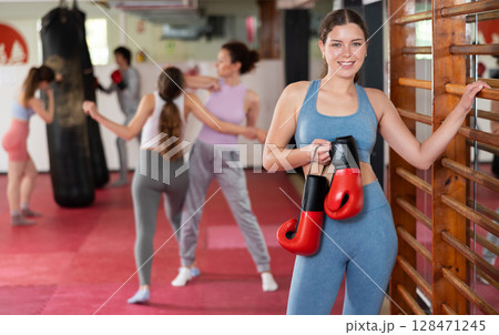 Woman athlete with boxing gloves pose before training in gym Woman athlete with boxing gloves pose before training in gym 128471245