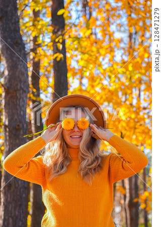 Woman faceless yellow sweater closing eyes with orange dahlia into camera Autumn Fall Bouquet for Thanksgiving holiday. Seasonal Warm colorful blossom flowers arrangement festive decoration 128471279