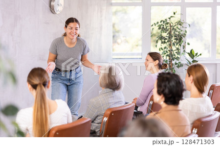 Young positive woman giving lecture in office Young positive woman giving lecture in office 128471303