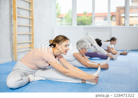 Group of women doing stretching in studio Group of women doing stretching in studio 128471322