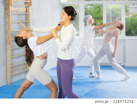 Woman practices blows to head of her attacking woman during self defense training 128471358
